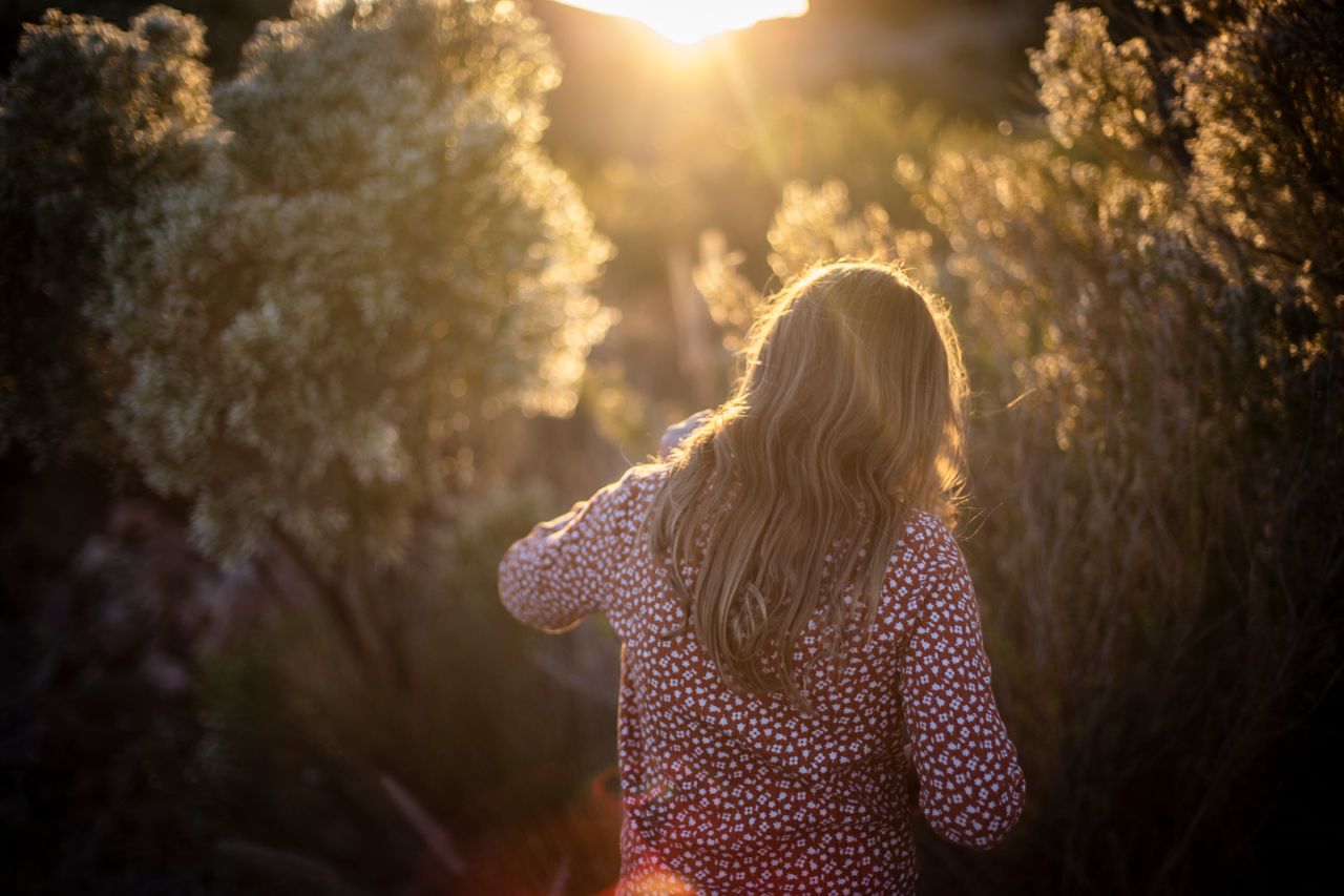 The Art of Drawing Readers In: Your attractive post title goes here A woman with blonde hair walks through a sunlit field at sunset, capturing tranquility.