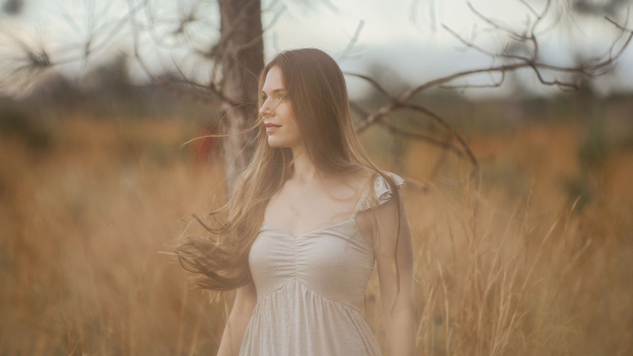About A serene portrait of a woman standing in a rural field, embracing nature.