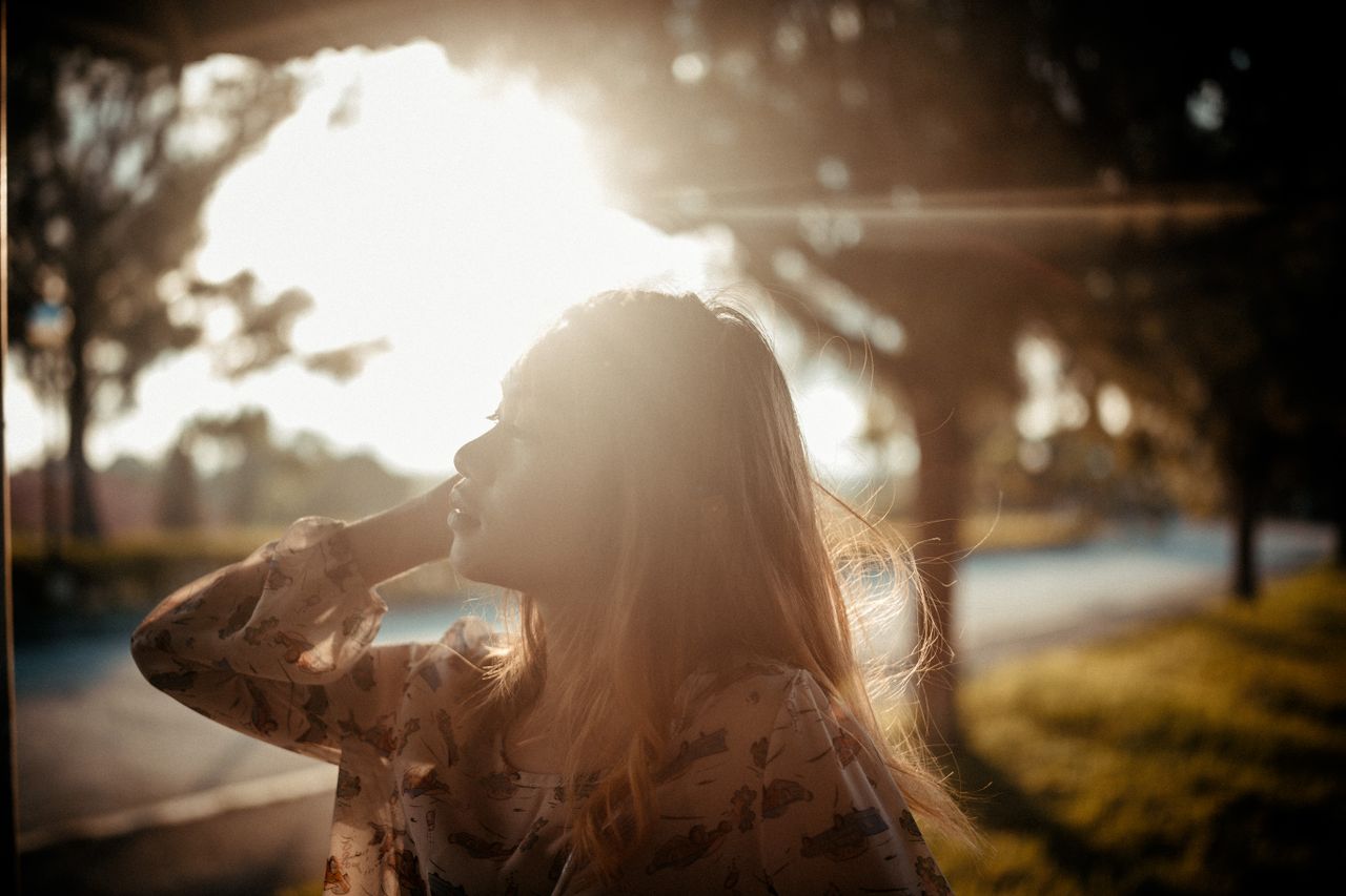 Services A woman with flowing hair enjoys the sunlight during golden hour outdoors.
