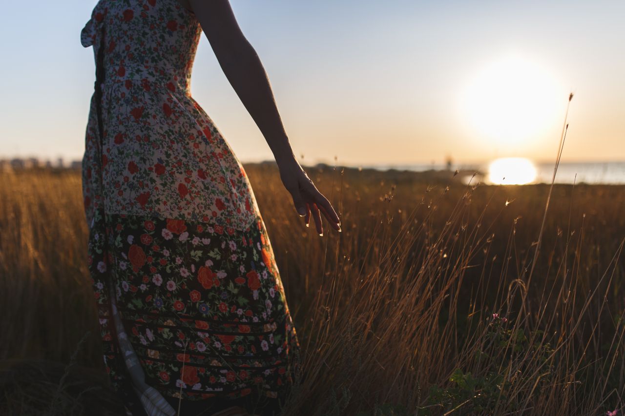 Mastering the First Impression: Your intriguing post title goes here Silhouette of a woman wearing a floral dress standing in a field at sunset.